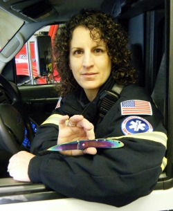 A picture of a woman holding a pocket knife in an EMT uniform