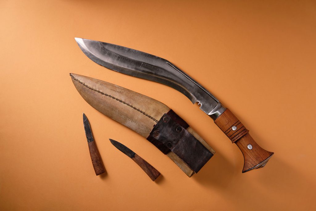 Ancient curved kukri knife on an orange background, scabbard, to