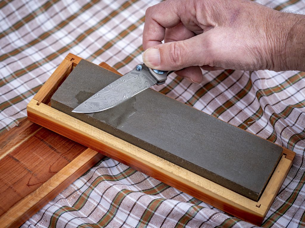 Pocket knife with unique Damascus patter getting a sharpened