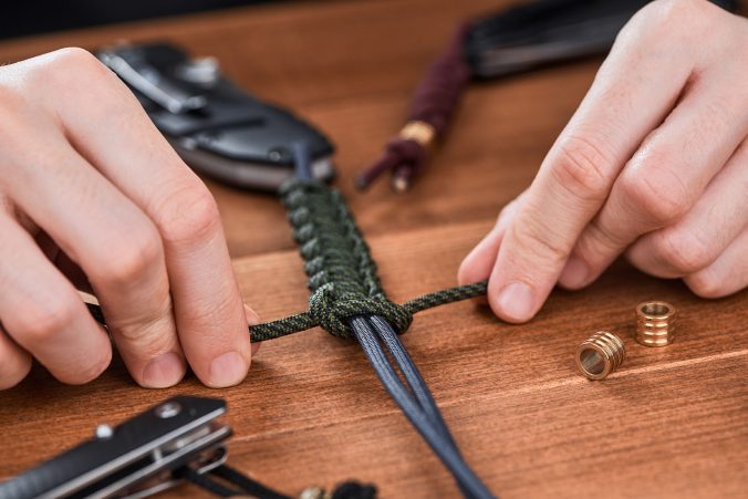 Close-up on hands making a paracord cobra lanyard for pocket knife